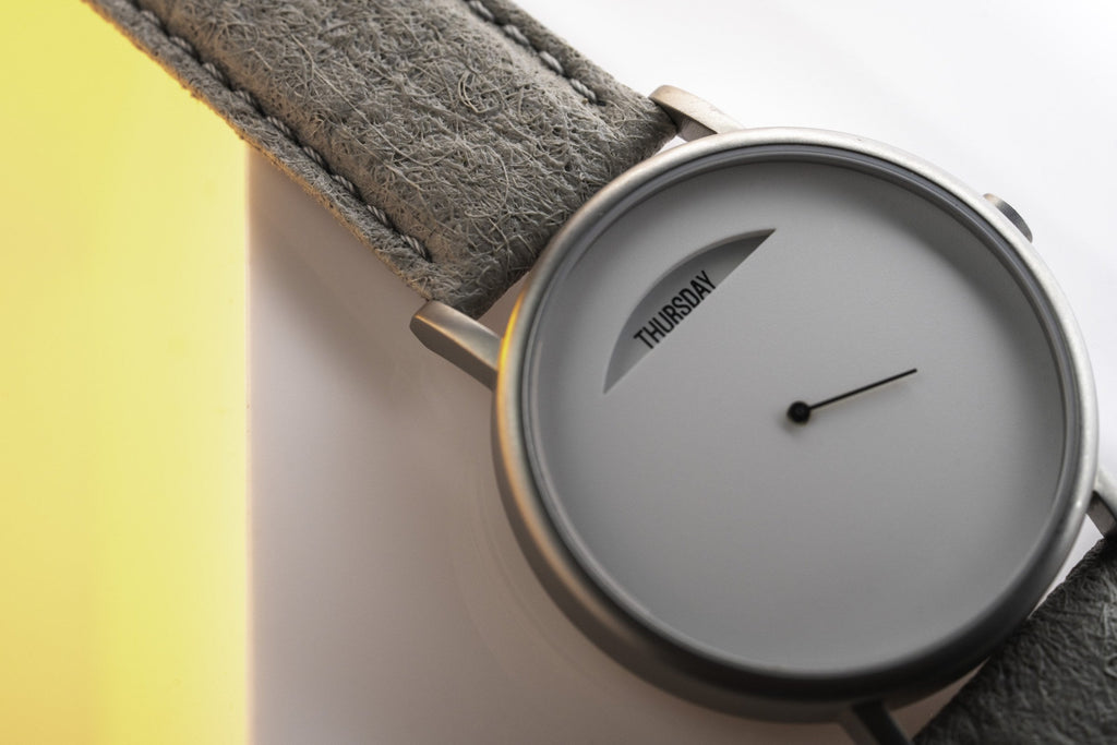 The Wednesday Daywatch — close-up of grey dial showing THURSDAY with grey suede strap detail