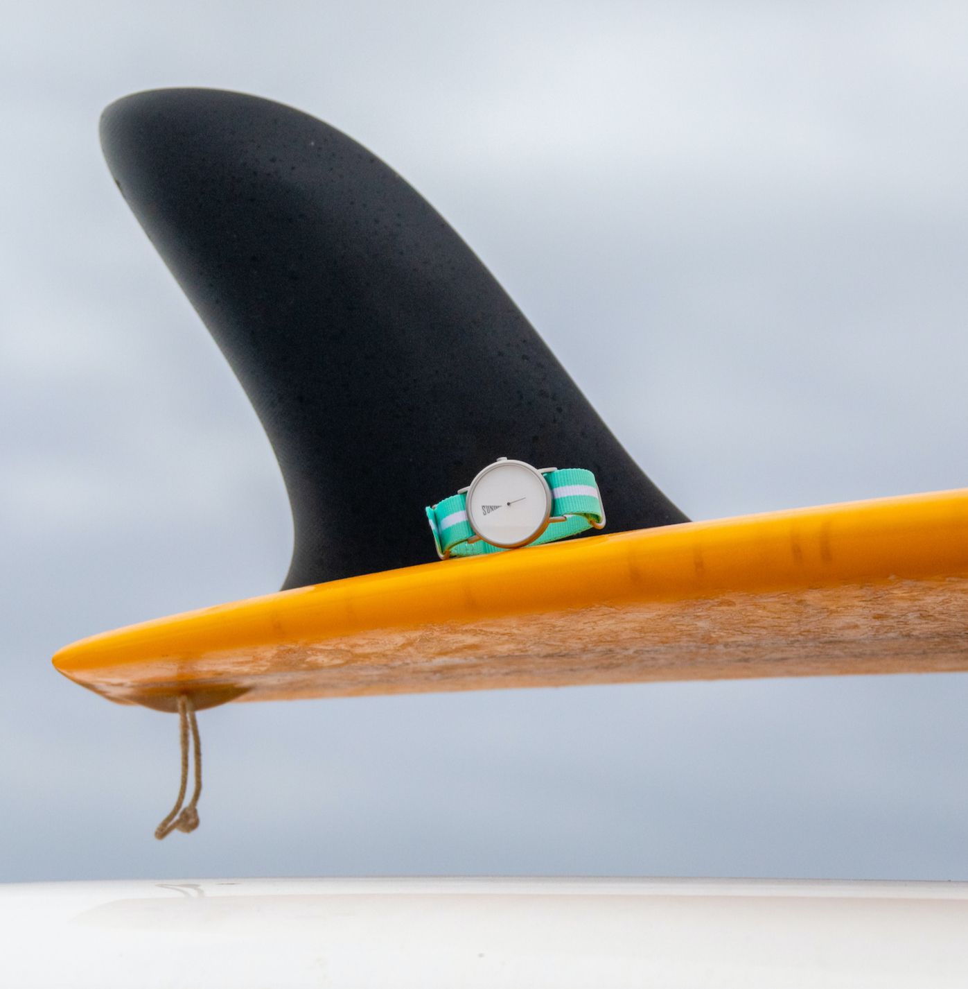 The Point White Daywatch dial face close-up showing downward triangle pennant and day display